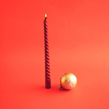 Red Candle And Gold Christmas Decoration Against Red Background