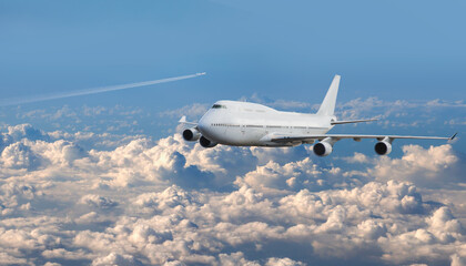 Wall Mural - White passenger airplane over the clouds  - Trail of white smoke from the airplane in the blue sky