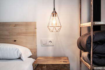 Poster - detail of the decoration of a bedroom with a bookshelf made of copper pipes, a wooden headboard and a side table made from a wooden stump