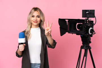 Reporter woman holding a microphone and reporting news over isolated pink background happy and counting three with fingers