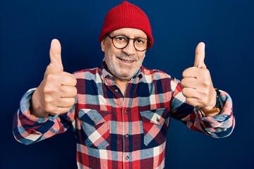 Canvas Print - Handsome mature man wearing hipster look with wool cap approving doing positive gesture with hand, thumbs up smiling and happy for success. winner gesture.