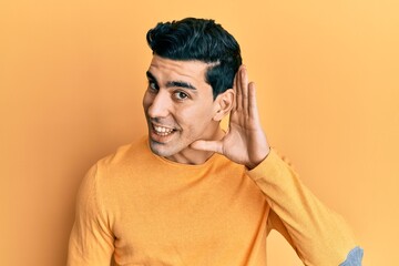 Wall Mural - Handsome hispanic man wearing casual clothes smiling with hand over ear listening and hearing to rumor or gossip. deafness concept.