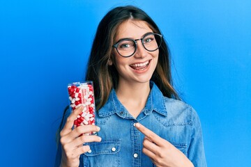 Poster - Young caucasian woman holding pills smiling happy pointing with hand and finger