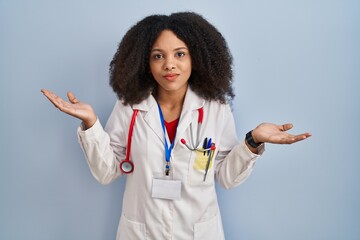 Wall Mural - Young african american woman wearing doctor uniform and stethoscope clueless and confused expression with arms and hands raised. doubt concept.