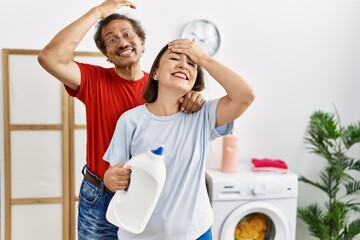 Sticker - Middle age interracial couple doing laundry holding detergent bottle stressed and frustrated with hand on head, surprised and angry face