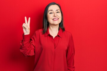 Wall Mural - Middle age hispanic woman wearing casual clothes smiling looking to the camera showing fingers doing victory sign. number two.