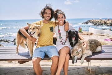 Wall Mural - Man and woman couple smiling confident hugging each other with dogs at seaside