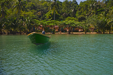 Wall Mural - Floating green boat in the sea with resort background