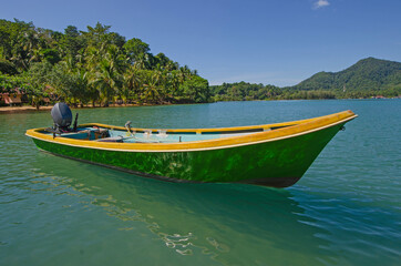 Wall Mural - Green boat with light reflection in clear water in the sea