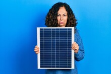 Middle Age Hispanic Woman Holding Photovoltaic Solar Panel Depressed And Worry For Distress, Crying Angry And Afraid. Sad Expression.
