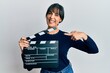 © Krakenimages.com - Young hispanic woman holding video film clapboard smiling happy pointing with hand and finger