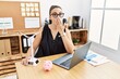 © Krakenimages.com - Young brunette woman working on solar windmill for cheaper electricity covering mouth with hand, shocked and afraid for mistake. surprised expression