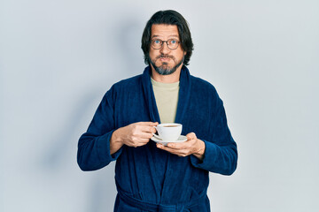 Poster - Middle age caucasian man wearing robe drinking coffee puffing cheeks with funny face. mouth inflated with air, catching air.