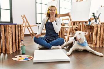 Poster - Caucasian young blonde woman at art studio covering mouth with hand, shocked and afraid for mistake. surprised expression