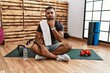 © Krakenimages.com - Young indian man sitting on training mat at the gym thinking concentrated about doubt with finger on chin and looking up wondering