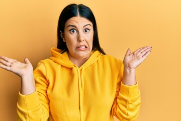 Poster - Beautiful brunette woman wearing casual sweatshirt clueless and confused with open arms, no idea and doubtful face.