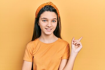 Sticker - Young brunette girl wearing casual orange t shirt smiling happy pointing with hand and finger to the side