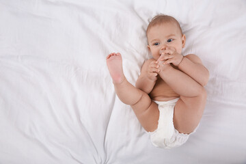 Canvas Print - Cute baby in dry soft diaper on white bed, top view. space for text