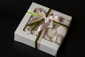 Wall Mural - Homemade marshmallow in a gift box. Tied with a ribbon tied to a bow. On a black background. Close-up.