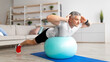 © Prostock-studio - Sporty mature man doing exercises with fitness ball at home, working out his back muscles, panorama, copy space