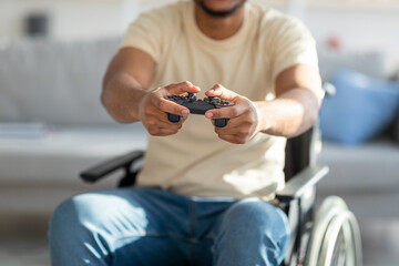 Cropped view of handicapped black guy in wheelchair enjoying online videogame, having fun at home, closeup