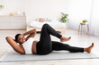 Plump young black woman exercising core muscles on sports mat at home