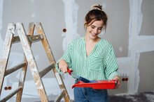 Capable happy young woman doing home renovations