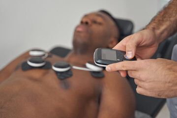 Wall Mural - Doctor using EMS device on young man pectorals