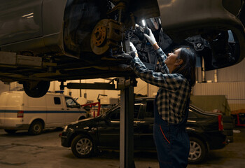 Wall Mural - Qualified repair shop technician checking and fixing a car