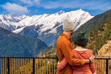 Tourist Couple Enjoy Scenic Himalayan Landscape With View Of Kinnaur Kailash Mountain Range From A View Point Near Kalpa Highway At Himachal Pradesh, India.