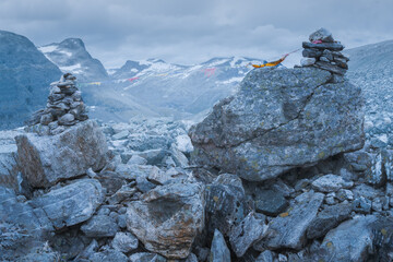 Wall Mural - Stone mound with dramatic mountain scenery in the back on the hiking trail to Trollvegen in Norway. Cloudy day in Norwegian nature. Hiking Scandinavia around Trollstigen road.