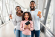Happy excited black family traveling, holding documents in airport