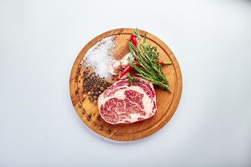 Wall Mural - Ribeye steak on the butcher's Board with rosemary, pepper and salt on a wooden table, prepared for cooking.