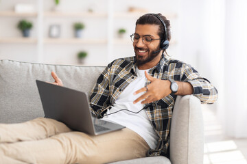 Cheerful indian guy reclining on couch in living room
