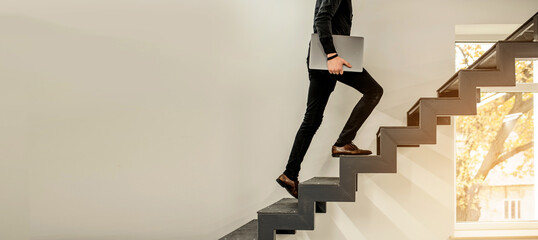 man climbing on a stairs and holding a laptop..