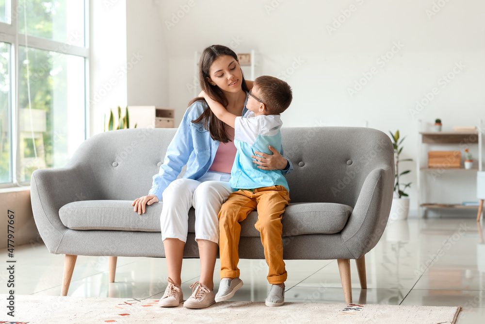 Little boy with his older sister hugging on sofa at home