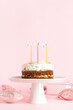 Stand with tasty birthday cake and balloons on pink background