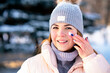 Portrait of beautiful woman applying cosmetic skin cream on face and hands, protecting from cold weather at winter season. Pretty girl take care of her skin outdoors on snowy nature background.