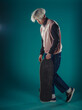 © qunica.com - Young adult man in casual outfit wear looking at camera, holding skateboard near face and standing at studio on blue background