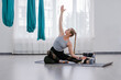 Fitness young woman doing yoga exercise in sportswear with strap near a window Pilates and stretching concept