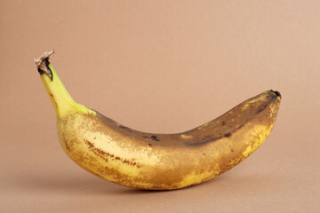 Wall Mural - Overripe banana on a light brown background. Ugly food concept.