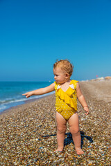 Poster - Baby is sitting on the beach by the sea. Selective focus.