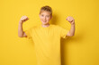 © Danko - Smiling boy in casual t-shirt making winner gesture over yellow background