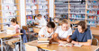 © JackF - Three schoolchildren, preparing for lessons in the school library, writes synopsis in an exercise book of the necessary ..material from the textbook, sitting at the desk
