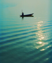 Silhouette Of Vietnamese Fisherman In Traditional Sampan Fishing Boat