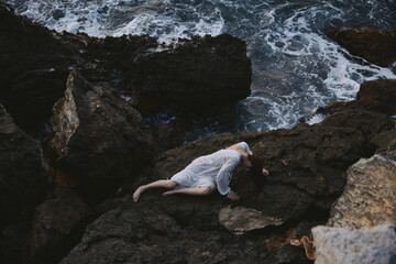 Poster - sensual woman lying on rocky coast with cracks on rocky surface landscape