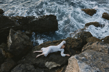 Poster - woman in a white dress lying on a stone in a white dress view from above