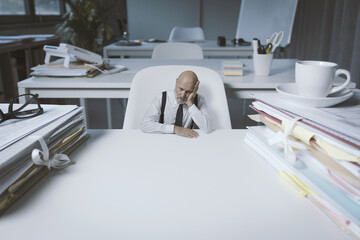 Wall Mural - Desperate tiny businessman sitting at desk