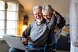 © NDABCREATIVITY - Happy senior couple using notebook at home and having fun together. Technology people concept