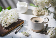Spring Composition With Cup Of Coffee, Old Book And White Lilac Beautiful Bouquet. Concept Of Spring And Comfort